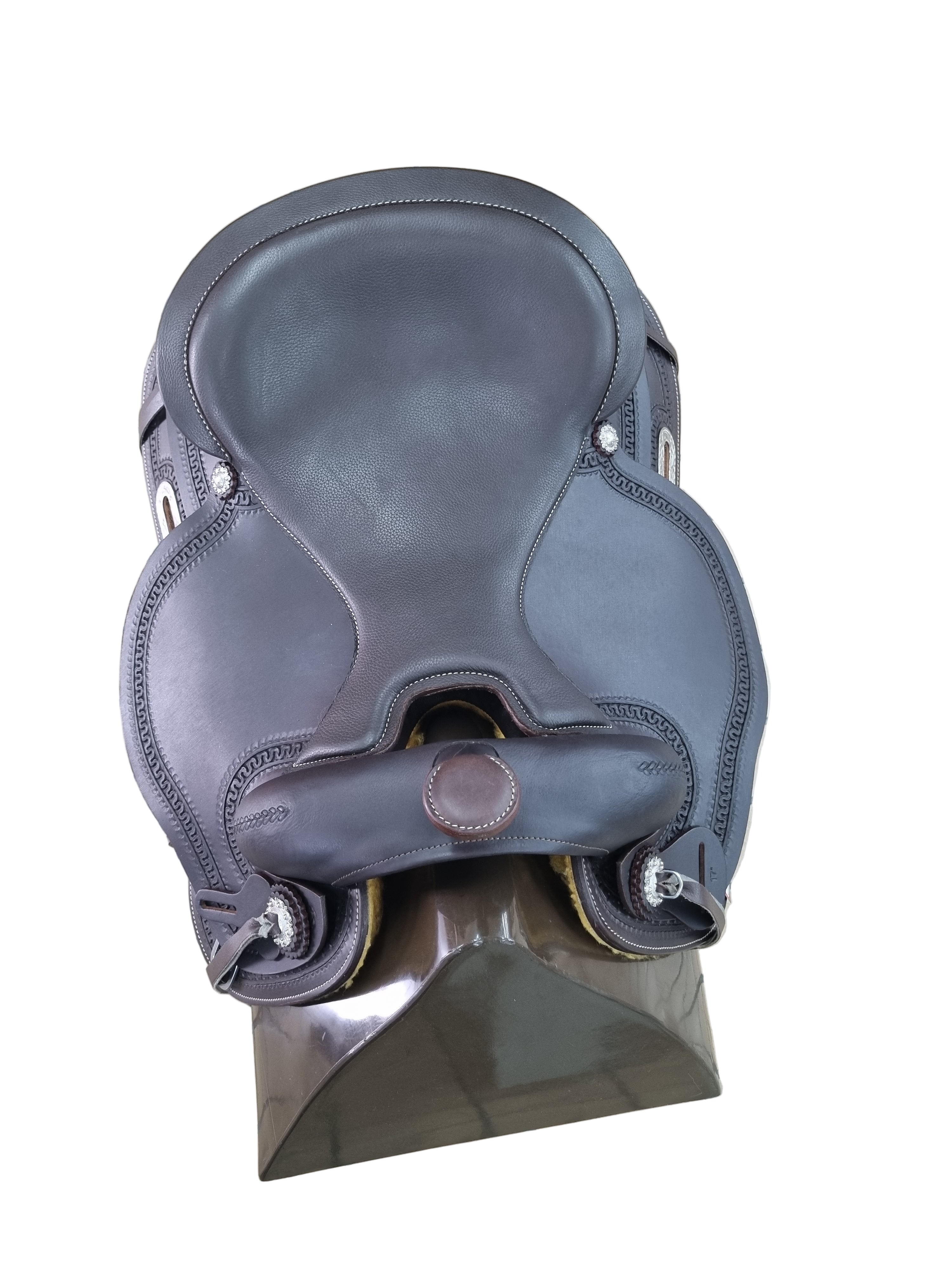 Brown leather saddle on a metal stand with a tiled floor background