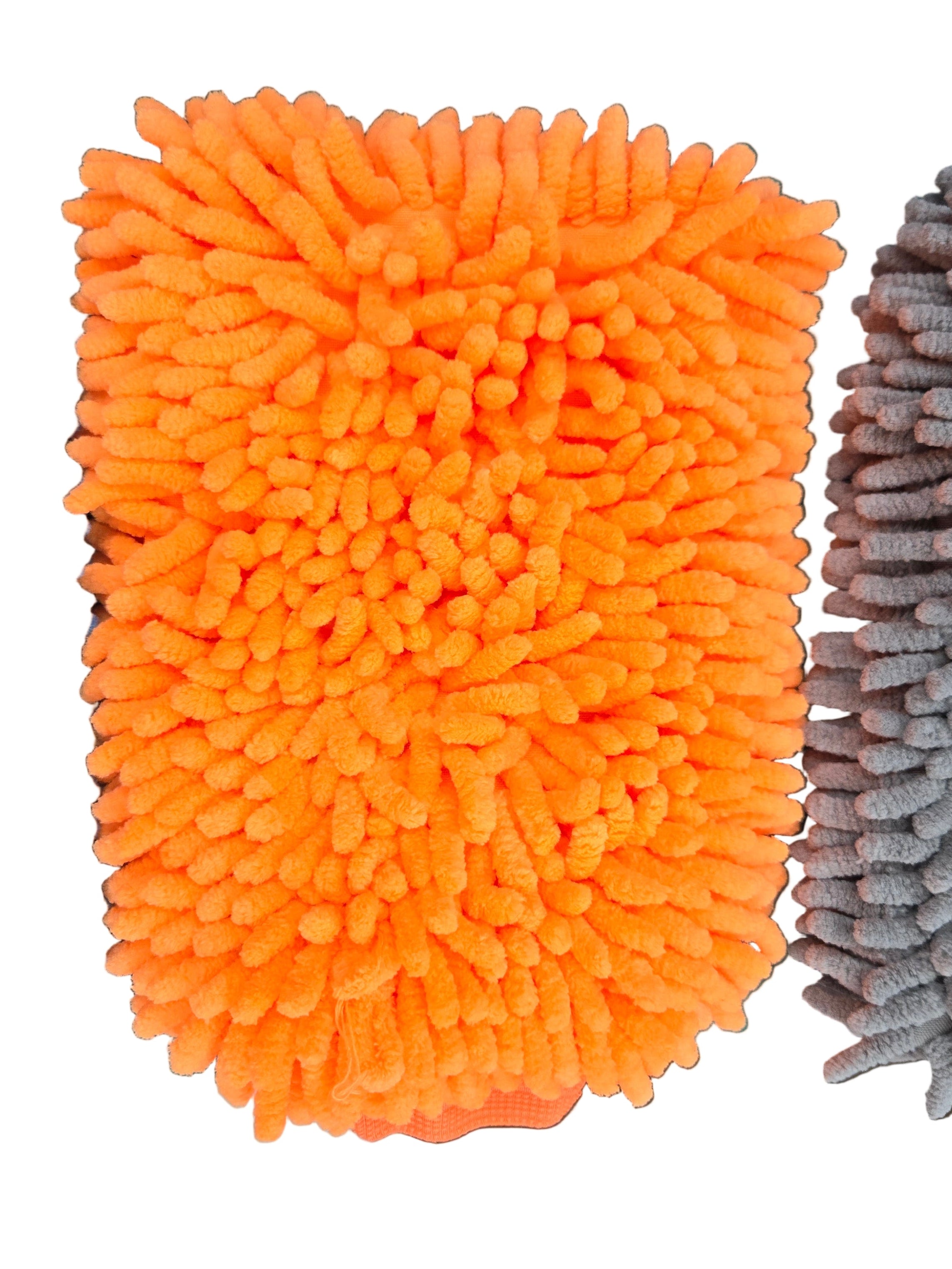 Orange, blue, and gray microfiber cleaning pads on a green surface with cardboard boxes in the background.