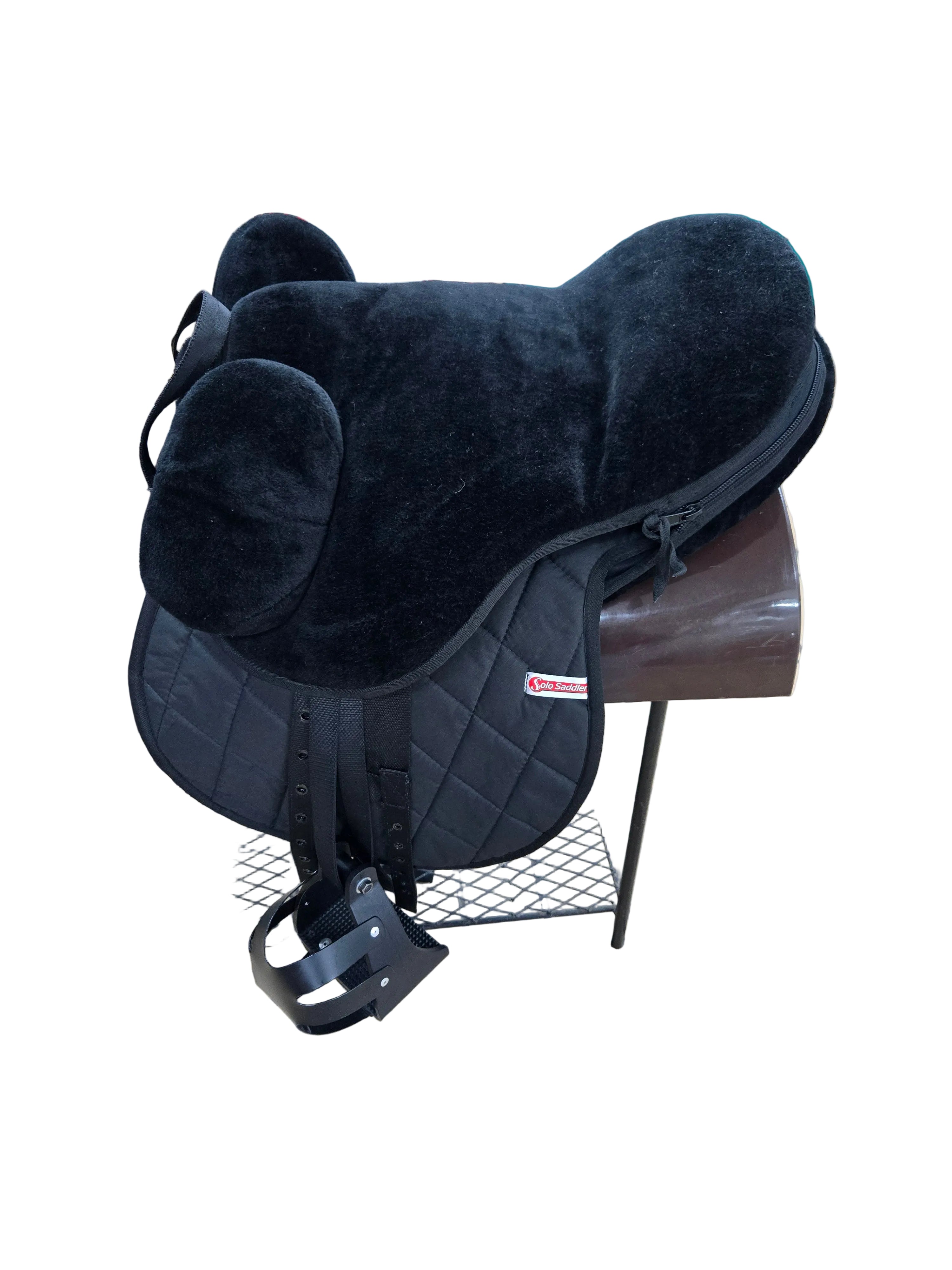 Black saddle on a stand with tiled floor and various items in the background
