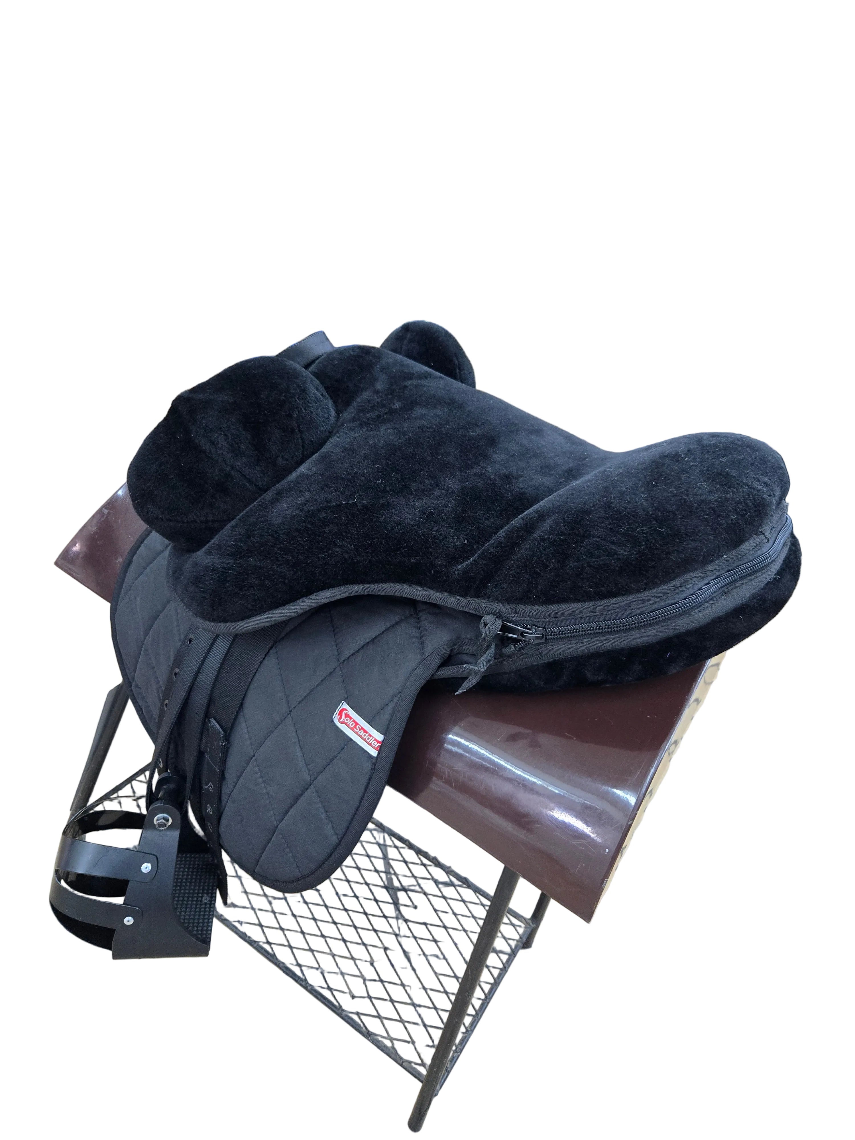 Black saddle on a stand in a store setting with various items in the background