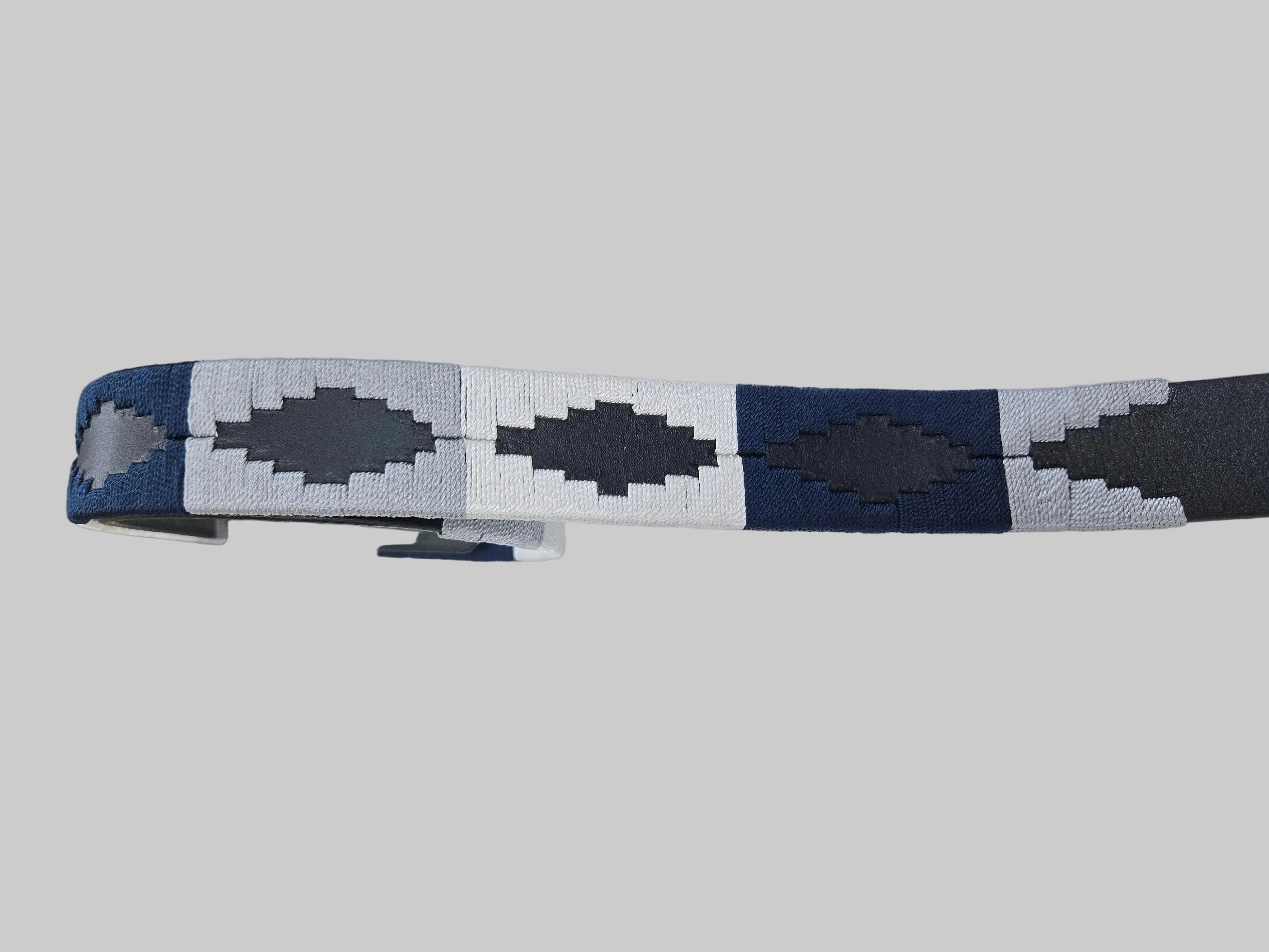 Close-up of a patterned belt on a white surface with a grid background