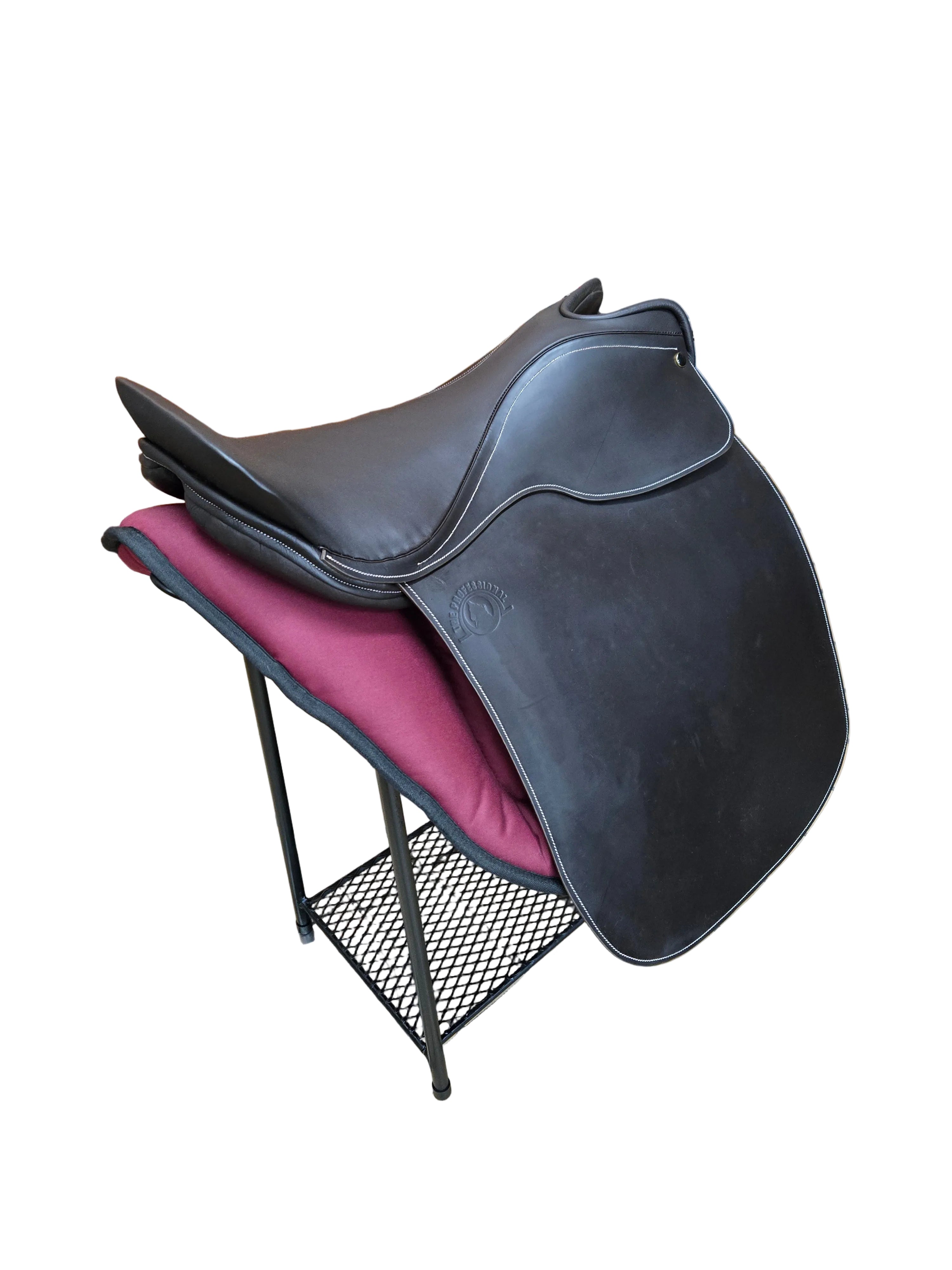 A black leather equestrian saddle displayed on a black metal stand with a burgundy cushion, set on a tiled floor inside a store.