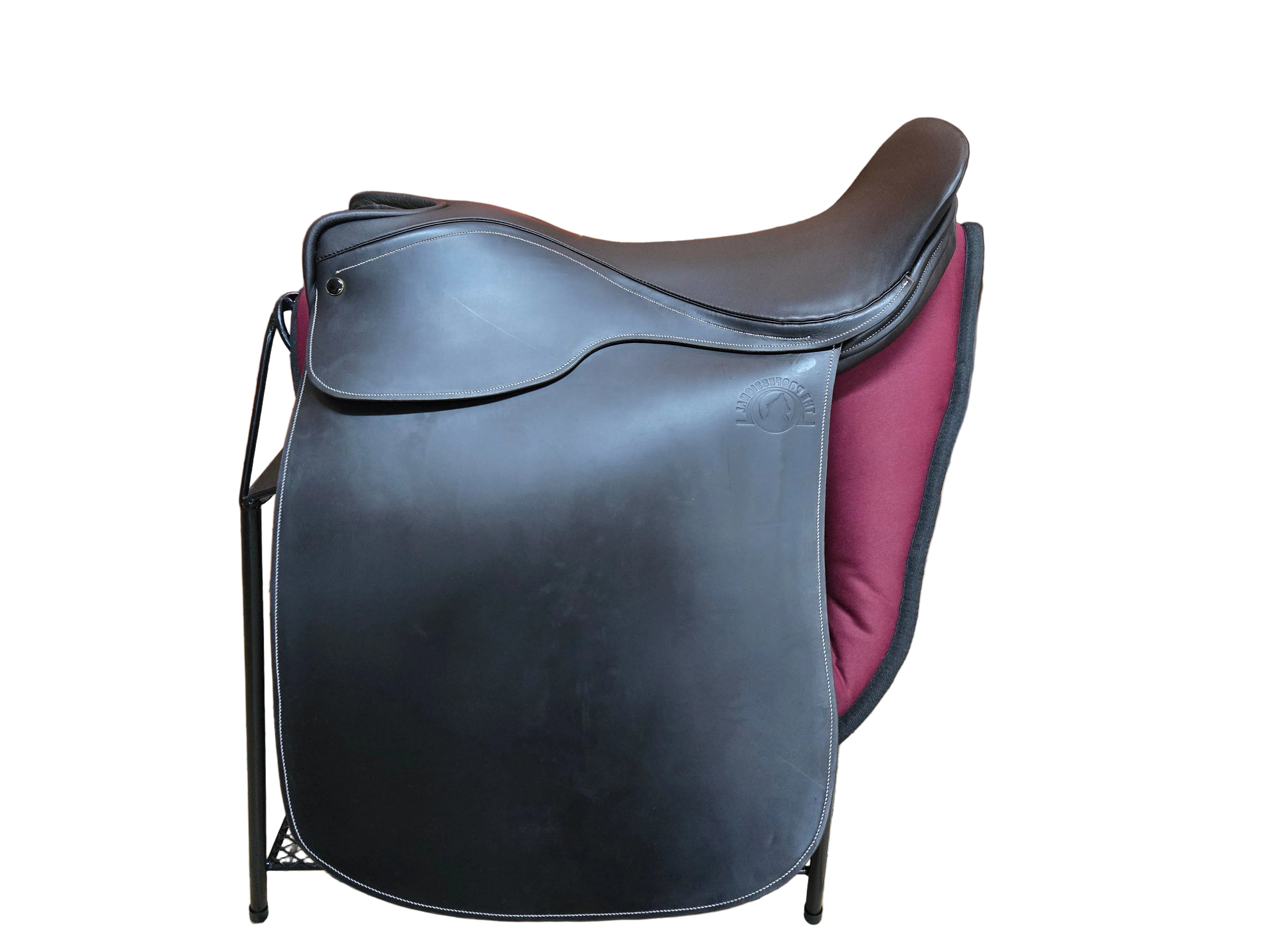 A black leather equestrian saddle with a dark burgundy velvet under-saddle pad, displayed on a black metal stand inside a store.