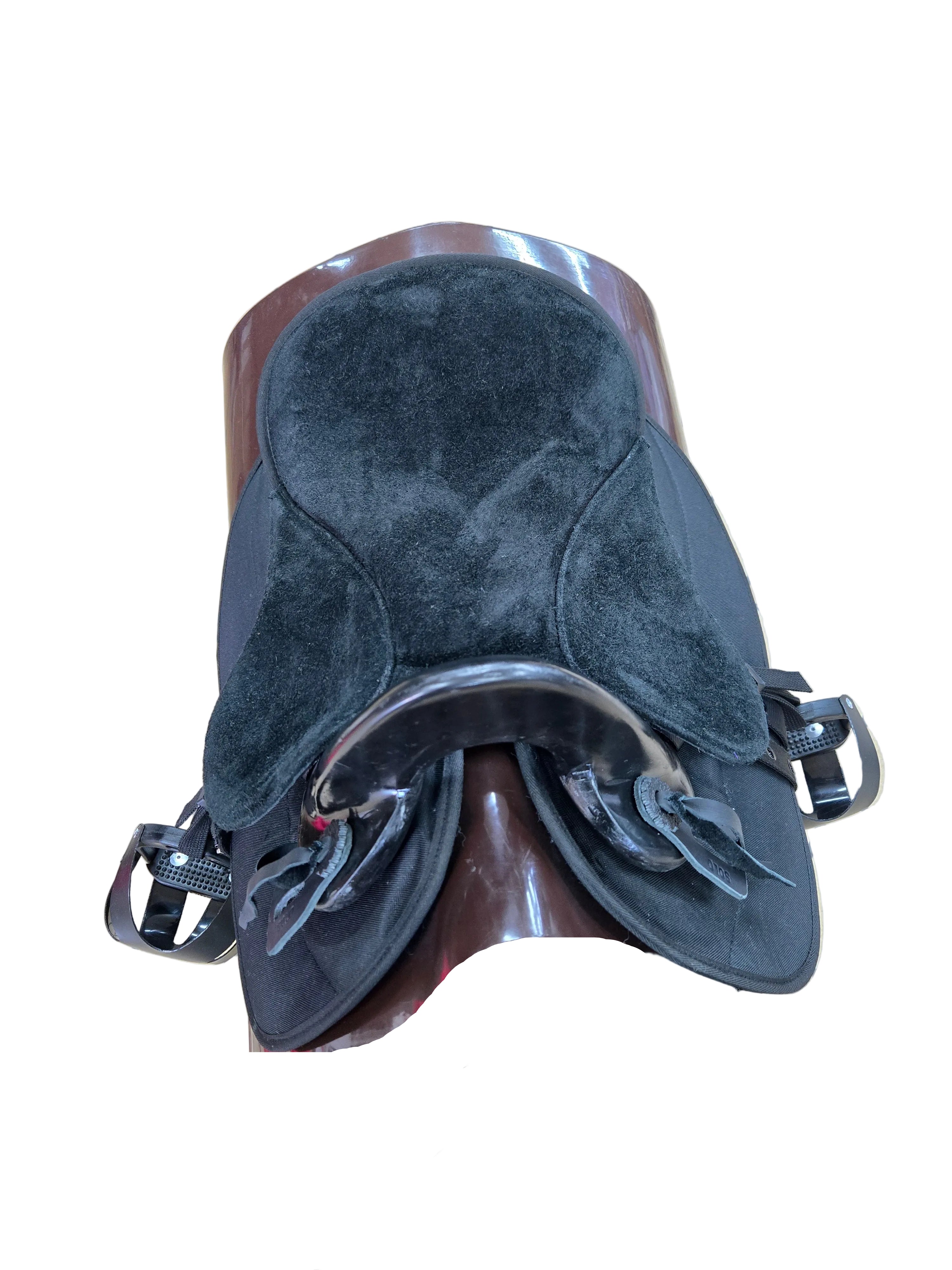 A black padded saddle pad with a curved shape, displayed on a brown wooden stand in a tiled indoor showroom.