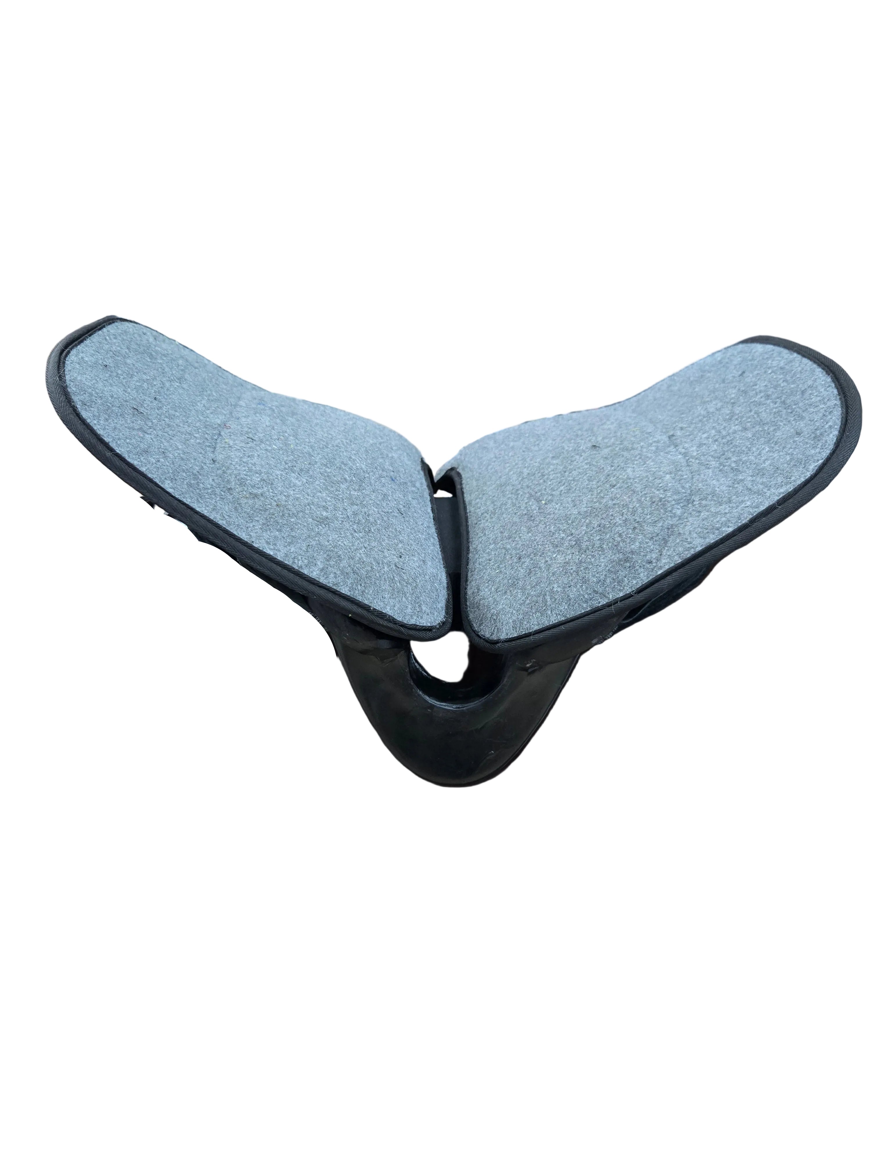 A black leather saddle with gray felt inserts on the seat, displayed on a dark brown wooden stand inside a hardware or tack shop.