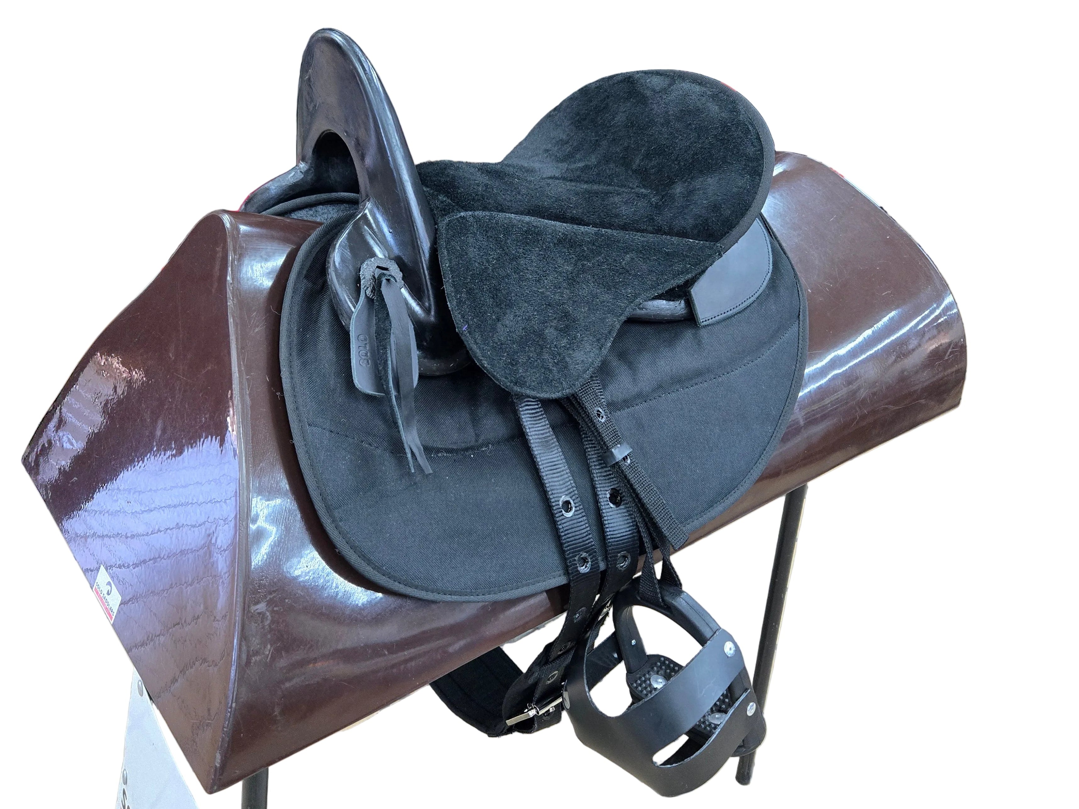 A black leather and suede equestrian saddle with a dark brown leather padded base, displayed on a stand in a retail store.