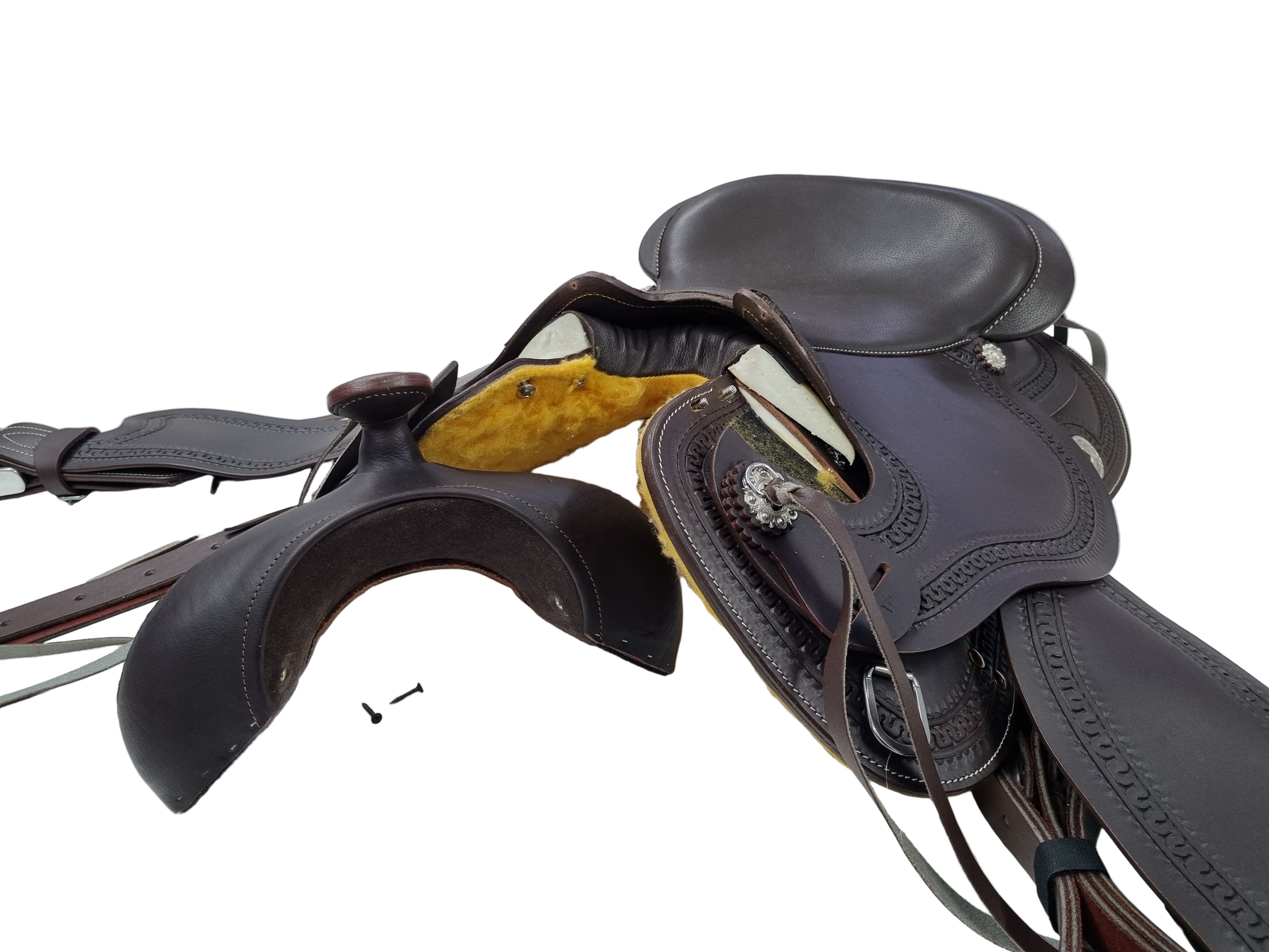 Brown leather saddle on a white surface with tools and a blurred background of shelves.